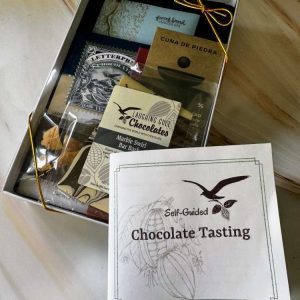 Seasonal tasting, chocolates in a white box with a clear top, and a booklet that says "Chocolate Tasting"